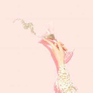 hand on champagne glass with confetti to symbolize party